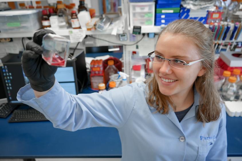 Lotta Truyen stands in Parrish Lab and holds up a flask with pink fluid