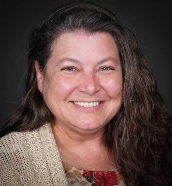 Headshot of a woman on a gray background. 