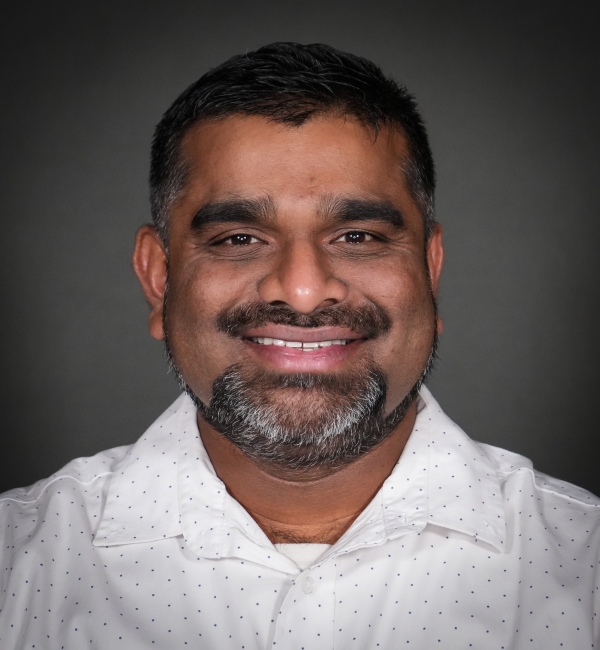 Headshot of a man on a gray background. 
