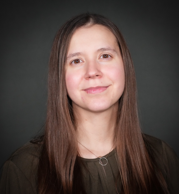 Headshot of a woman on a gray background. 