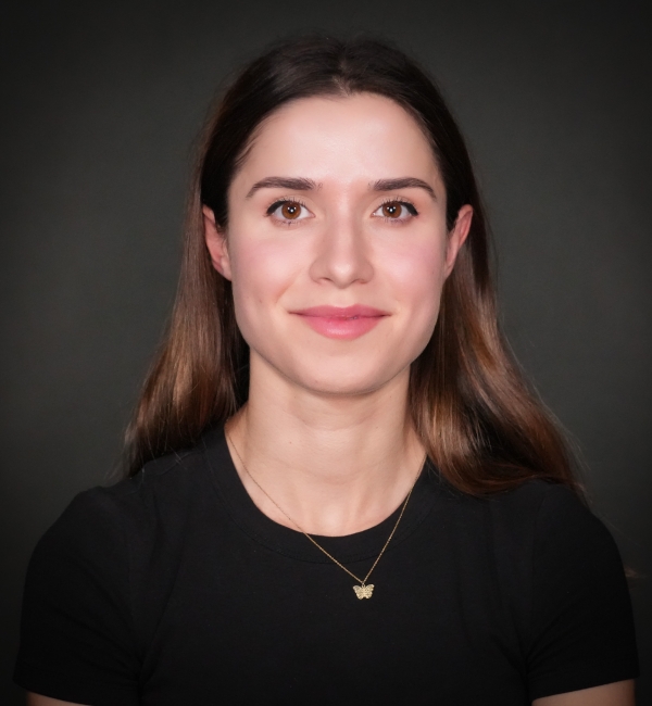 Headshot of a woman on a gray background. 