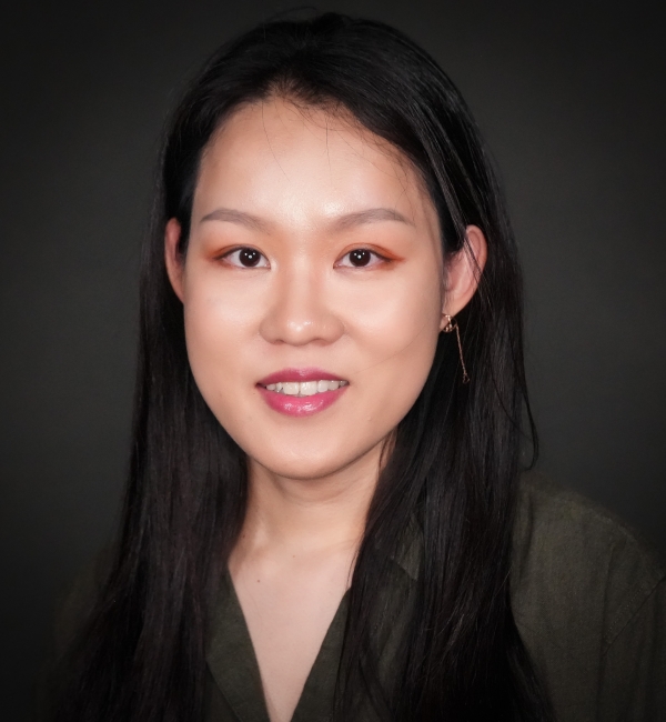 Headshot of a woman on a gray background. 