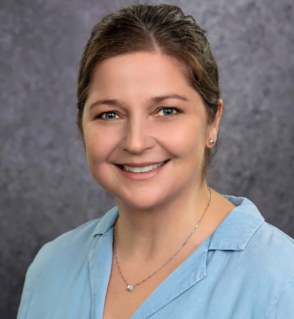 Michelle Delco in a gray background with a light blue blouse.