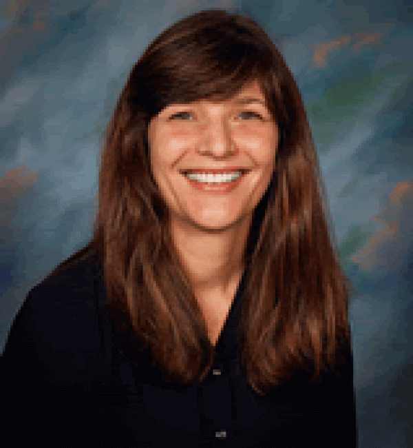 Julia Felippe in a blueish background wearing a black cardigan.
