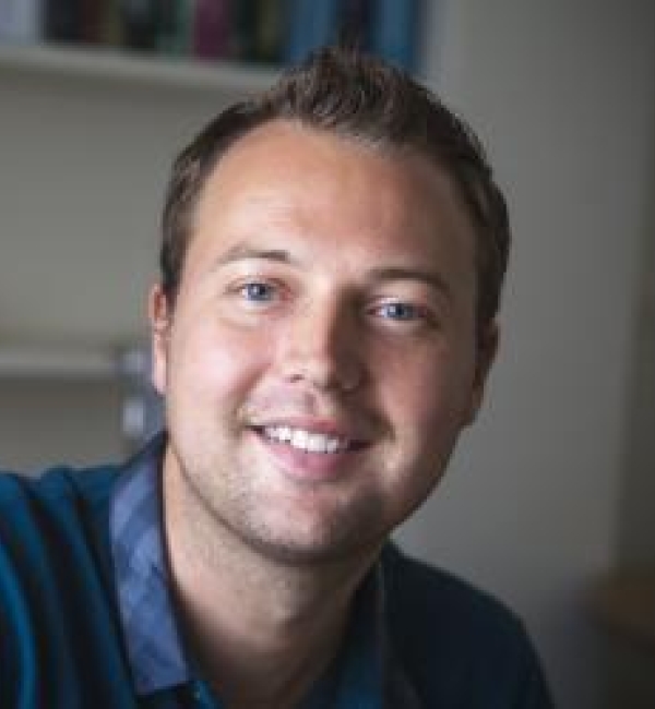 Robin Dando in office wearing a turquoise cardigan and striped blue dress shirt.