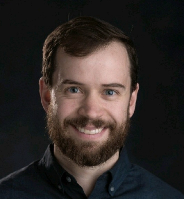 Portrait photograph of Dr. Daniel Bondeson smiling in front of a dark background.