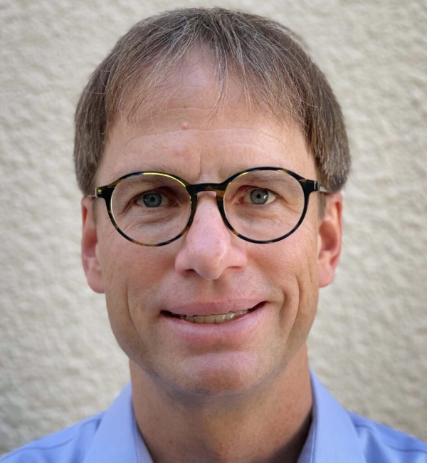 Jan Lammerding in front of a white background with black rimmed glasses and a light blue collared shirt.