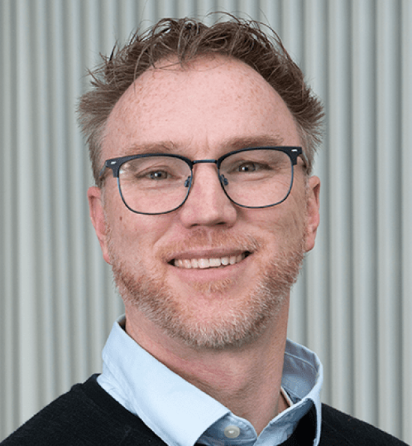 Jonathan Butcher in a light, blue-collared shirt and a black cardigan.