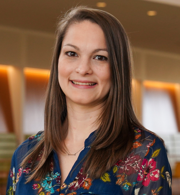 Jennifer Prieto wearing a floral blouse standing in front of the 2nd floor CVM Atrium.