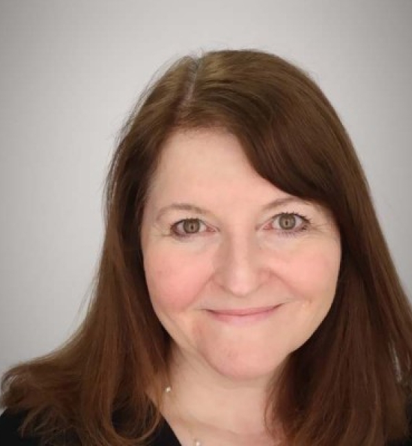 Kimberly O'Brien smiling while standing in front of an off-white background.