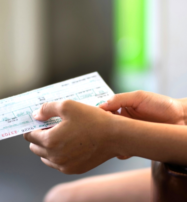 Hands holding a ticket or form, with a brown wristwatch visible on the left wrist