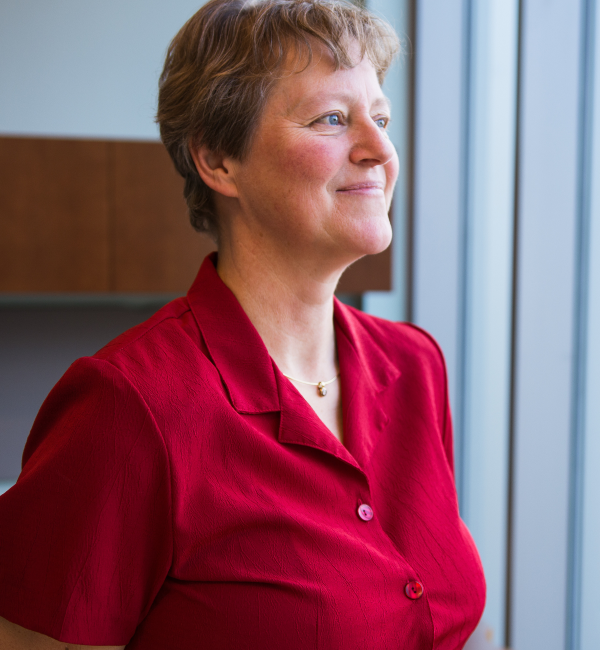 A woman wearing a red shirt looking into the distance. 