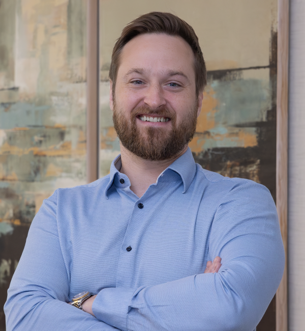 Portrait photograph of Dr. Peter Westcott smiling at the camera and crossing his arms