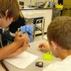 Two students leaning over a table examining a learning module