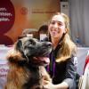 Dr. Aly Cohen kneels next to a giant dog sitting in front of a CVM booth