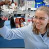 Lotta Truyen stands in Parrish Lab and holds up a flask with pink fluid