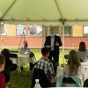 Dean Warnick speaks to a group of faculty in the new department beneath a tent outside the college