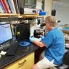 Rod Getchell at a microscope with the Aquatic Animal Health Program