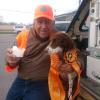 A man in hunting attire holds a pup cup for his eager dog