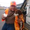 A man in hunting attire holds a pup cup for his eager dog