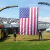 Two people standing beneath an enormous American flag that is hung between two tractors