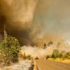 A car driving away from a smoke caused by a wildfire 