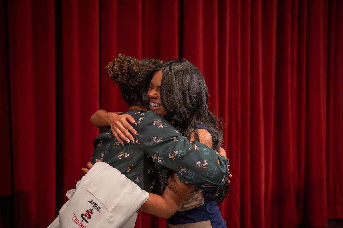 Student and mentor hug on stage